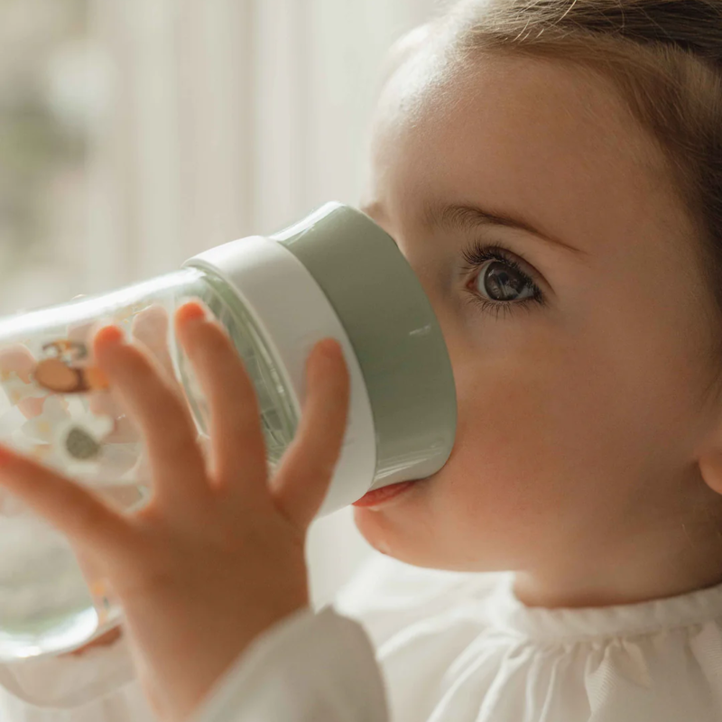 Criança pequena a beber do copo de treino aprendizagem 360º Little Dutch Mepal Little Farm, mostrando a facilidade de uso.