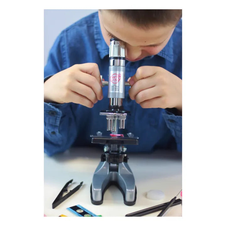 Um jovem a observar através do microscópio Buki Zoom 1200x, ajustando o foco com as mãos.