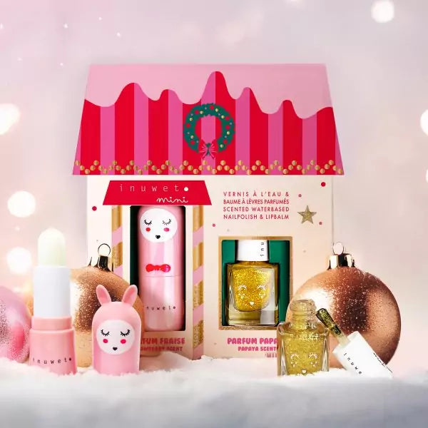 Conjunto de bálsamos labial e verniz Inuwet Strawberry e Papaia em caixa decorada em forma de casa de Natal, com enfeites e luzes desfocadas.