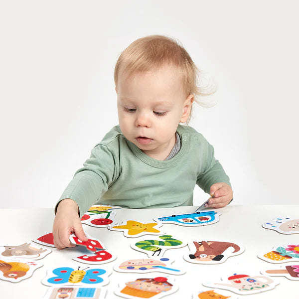 Criança pequena com cerca de 15 meses a brincar e a montar um dos puzzles Banana Panda Puzzles Pares Felizes, focada na peça de um cogumelo.