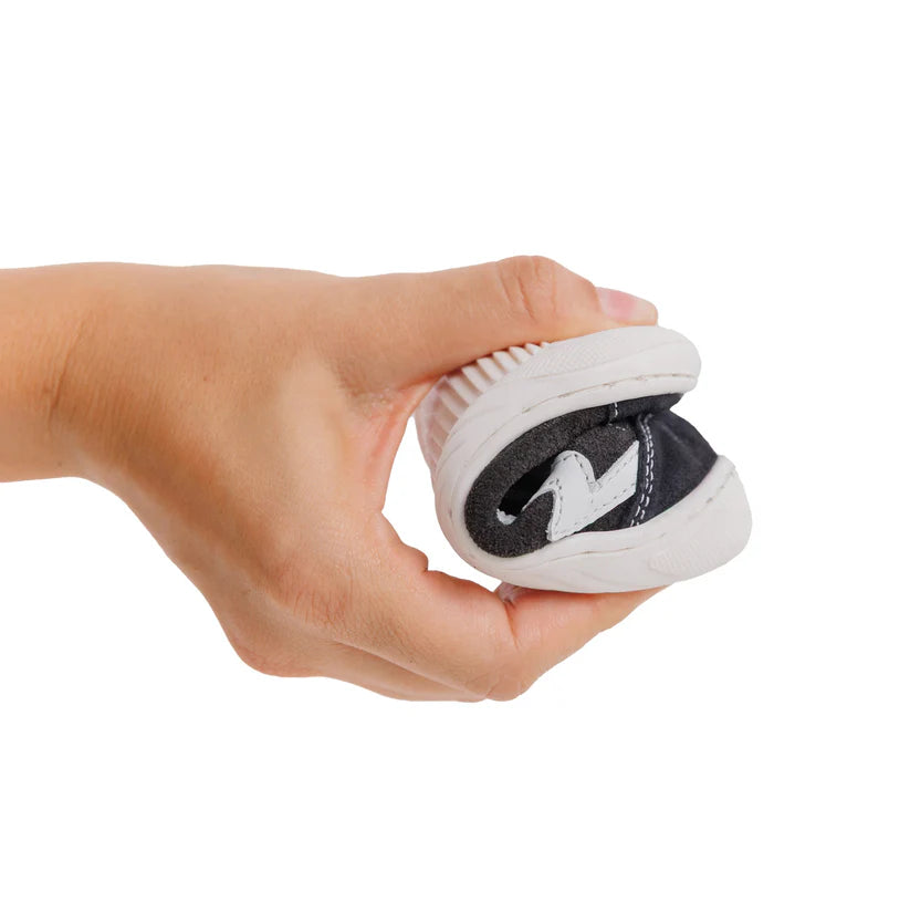 Mão a demonstrar a flexibilidade da sola de uma sapatilha Bunny Barefoot Zebra Preto, dobrando-a ao meio.