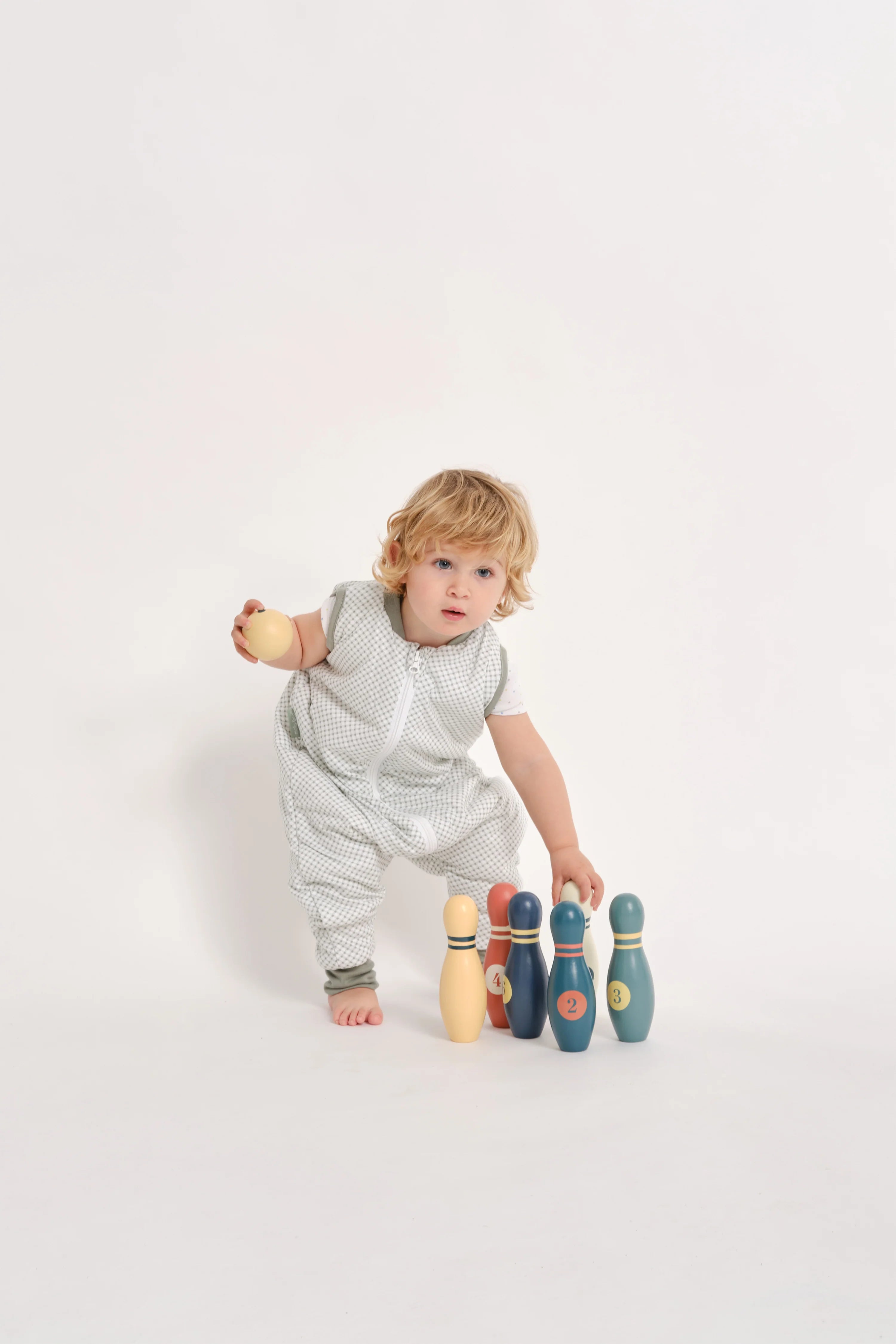 Criança a brincar com pinos de bowling, vestindo o saco de dormir MolisandCo TOG 1.0 com pés VICHY GREEN, enfatizando a liberdade para atividades.