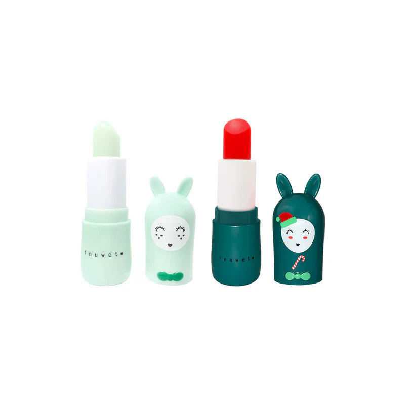 Bálsamos labiais Inuwet de maça (verde) e cereja (vermelho) fora das suas embalagens em forma de coelho, mostrando o produto exposto.