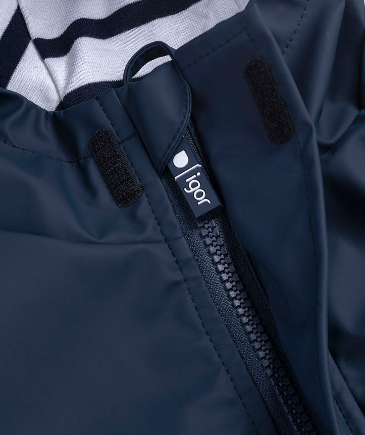 Detalhe do fecho de correr do casaco Igor impermeável marinho, com aba de velcro e etiqueta "igor" no puxador, mostrando o forro às riscas do capuz.