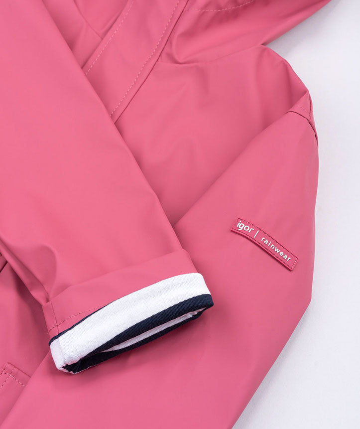 Detalhe da manga do casaco Igor impermeável framboesa, mostrando a etiqueta "igor rainwear" e o punho dobrado com riscas.