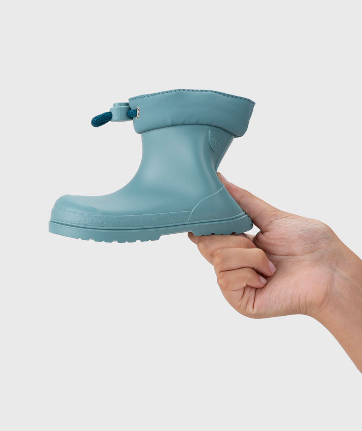 Uma galocha Igor MENDI Turquesa sendo segurada pela mão, destacando a sua leveza e flexibilidade.