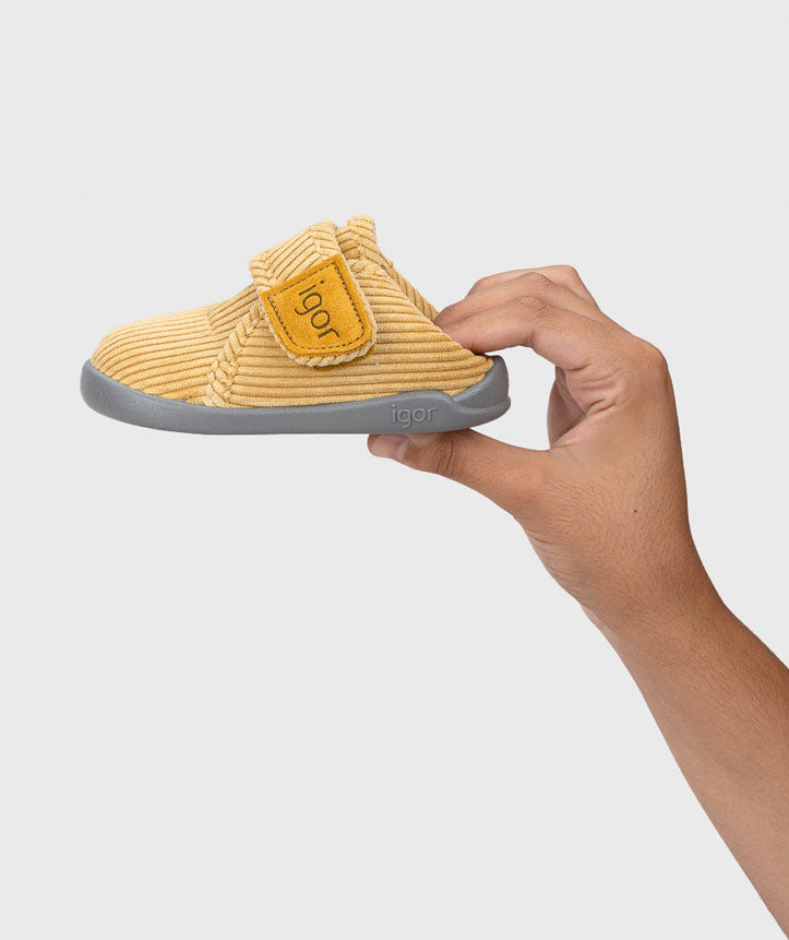 Mão a segurar uma pantufa Igor Barefoot Homie Pana Amarillo, destacando a leveza.