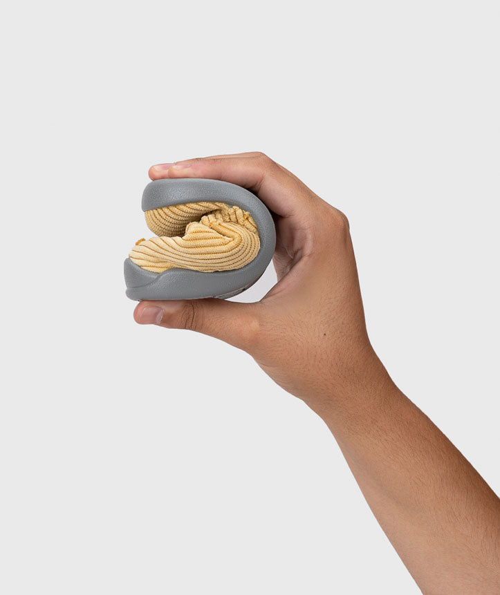 Mão a dobrar uma pantufa Igor Barefoot Homie Pana Amarillo, demonstrando a flexibilidade da sola.