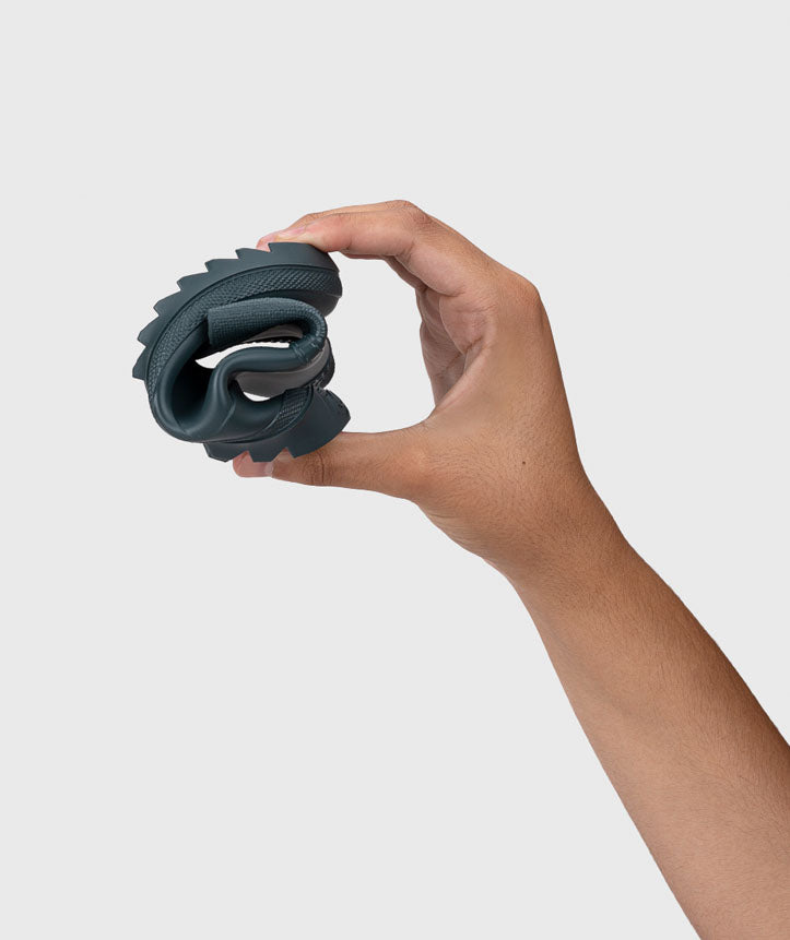 Mão a demonstrar a flexibilidade extrema da sola da galocha Igor Verona Gris Petroleo, dobrando-a ao meio.