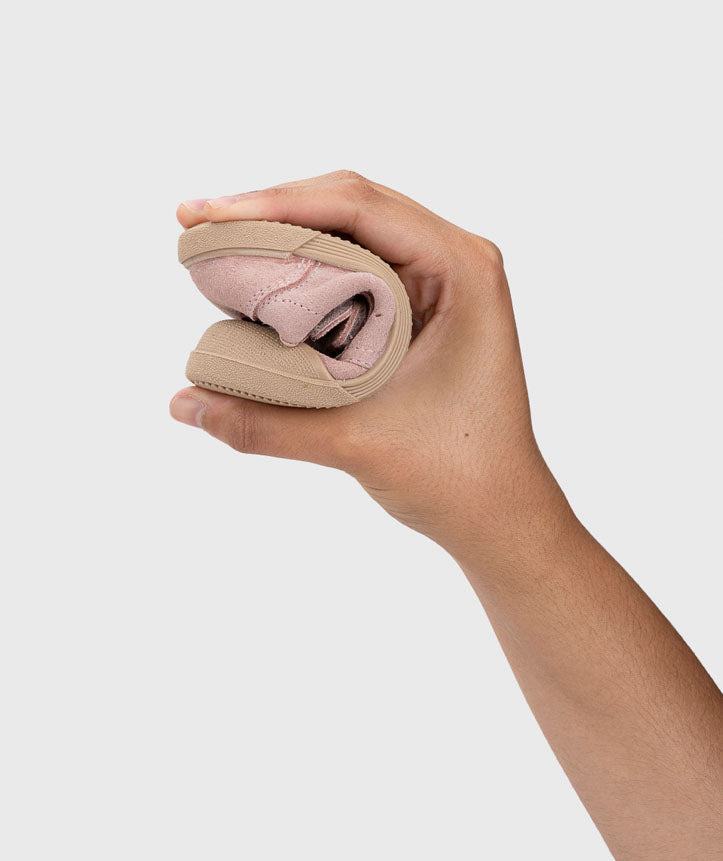 Mão a dobrar sapatilha Igor Barefoot Tennis Suede Rosa, evidenciando a extrema flexibilidade da sola.