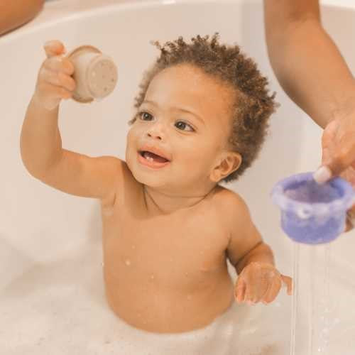 Bebé na banheira a brincar com os vasos de silicone Tiny Twinkle, mostrando a diversão e a interação com a água.