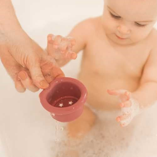 Bebé na banheira a brincar com um dos vasos de silicone Tiny Twinkle, mostrando o uso na hora do banho.