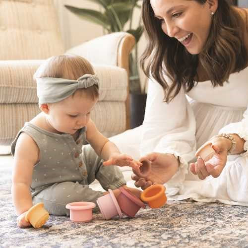 Bebé a brincar com os vasos de silicone Tiny Twinkle, interagindo com a mãe num ambiente aconchegante.