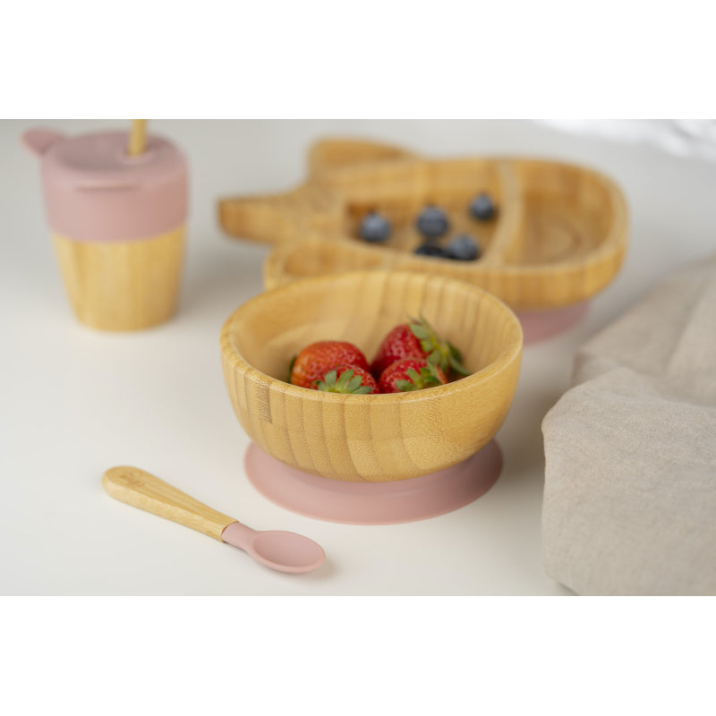 Conjunto de alimentação Citron rosa com tigela de bambu cheia de morangos, colher de silicone, copo e prato de bambu em fundo branco.