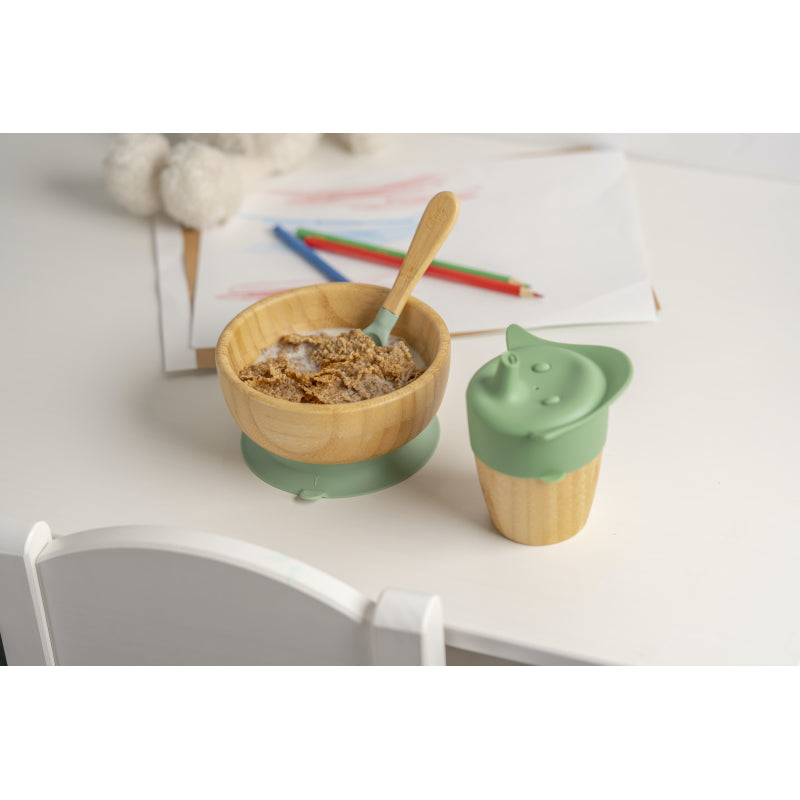 Conjunto de alimentação Citron verde com tigela de bambu cheia de cereais e colher, ao lado de um copo de bambu, numa mesa com desenhos.