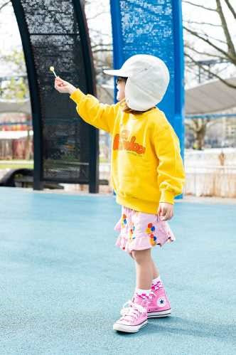 Criança a usar KIETLA Chapéu c/abas de orelha num parque infantil.