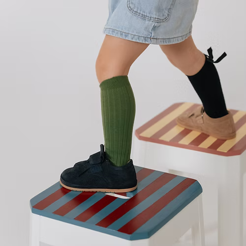 Uma criança a usar sapatilhas Rooties Carneiras PiuPiu Azul Marinho, a subir degraus, demonstrando a liberdade de movimento.