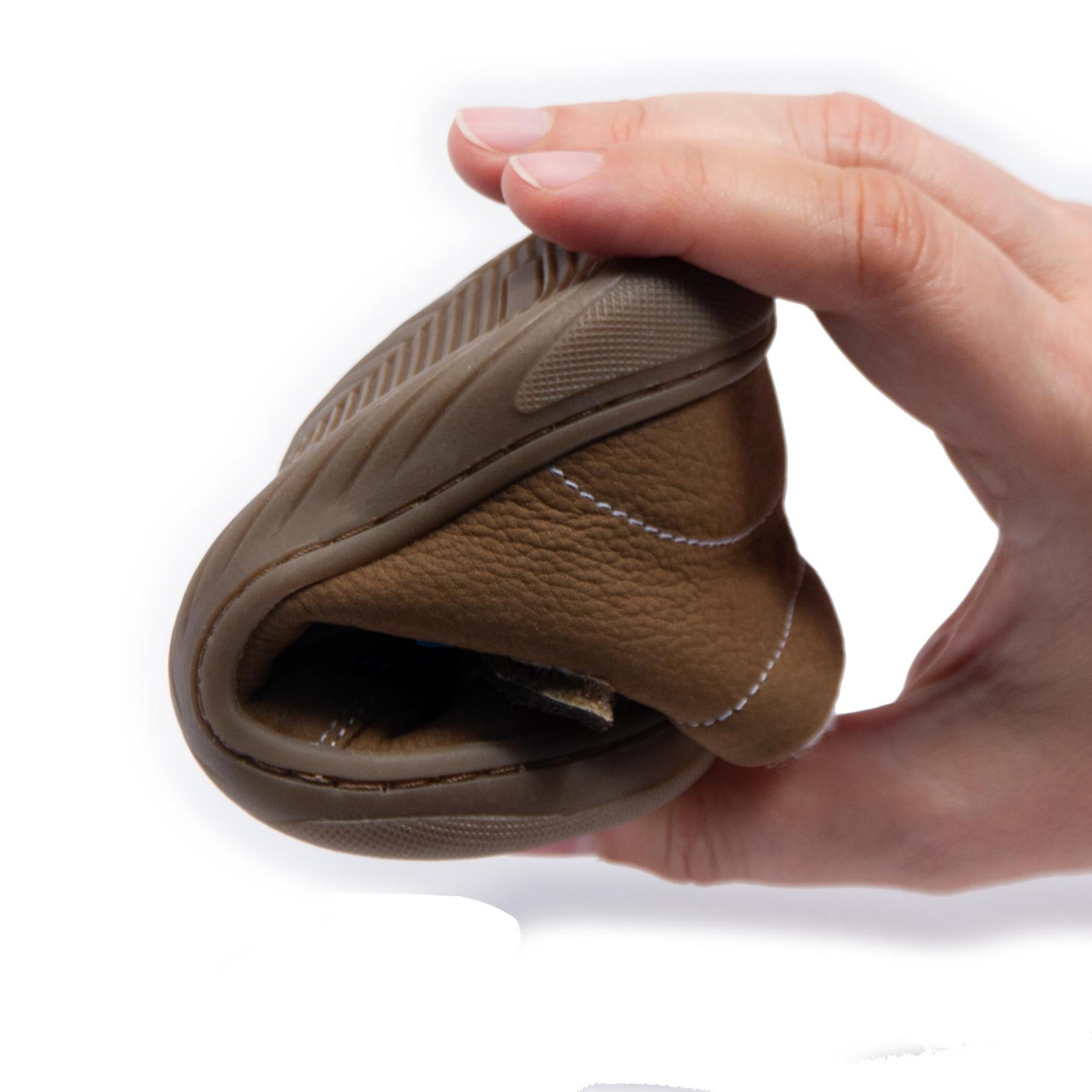 Demonstração da flexibilidade das botas barefoot Dodo Shoes em tom de canela, com sola maleável que permite o movimento natural dos pés e promove o seu desenvolvimento saudável.