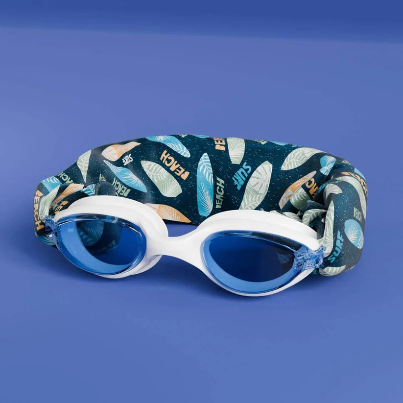 Waterplops Óculos para Piscina Surf de armação branca e lentes azuis, com a banda elástica de padrão de pranchas de surf dobrada atrás, sobre fundo azul.