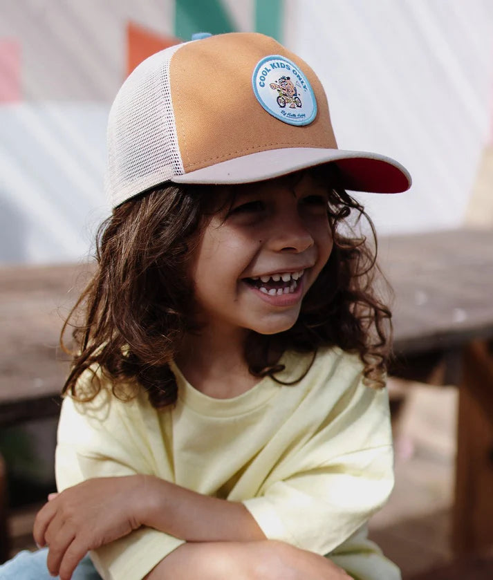 Criança sorridente a usar o boné Hello Hossy Biker, destacando o patch e a aba plana.