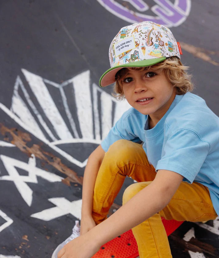 Criança sorrindo usando o boné Hello Hossy San Francisco com padrão divertido e aba verde, ideal para um look moderno.
