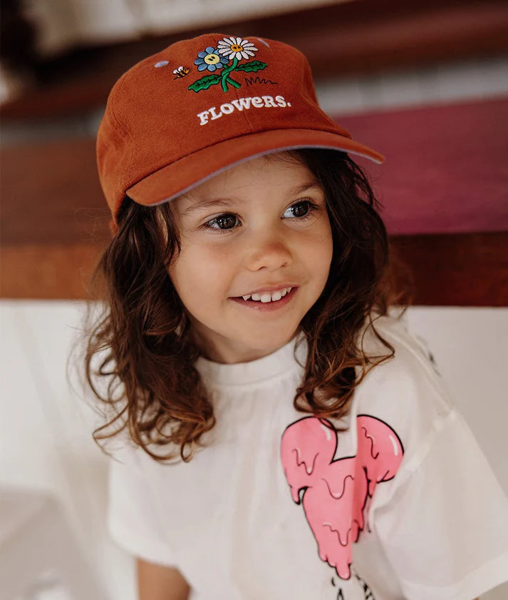 Criança sorridente com boné Hello Hossy Flowers de linho e algodão. Conforto e estilo para os mais pequenos.
