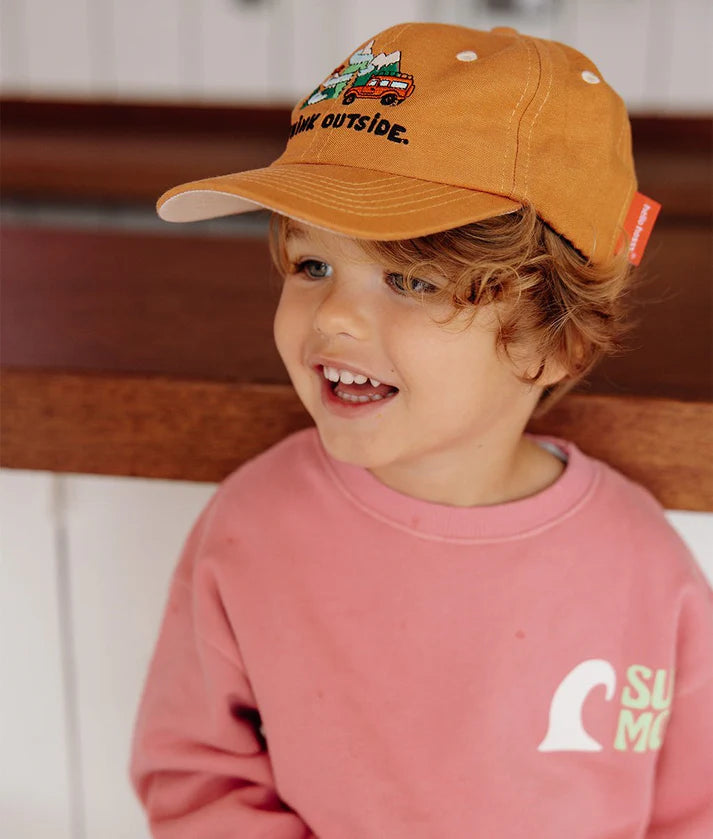 Menino sorridente usa boné Hello Hossy Outside de linho e algodão, mostrando ajuste e estilo para crianças.