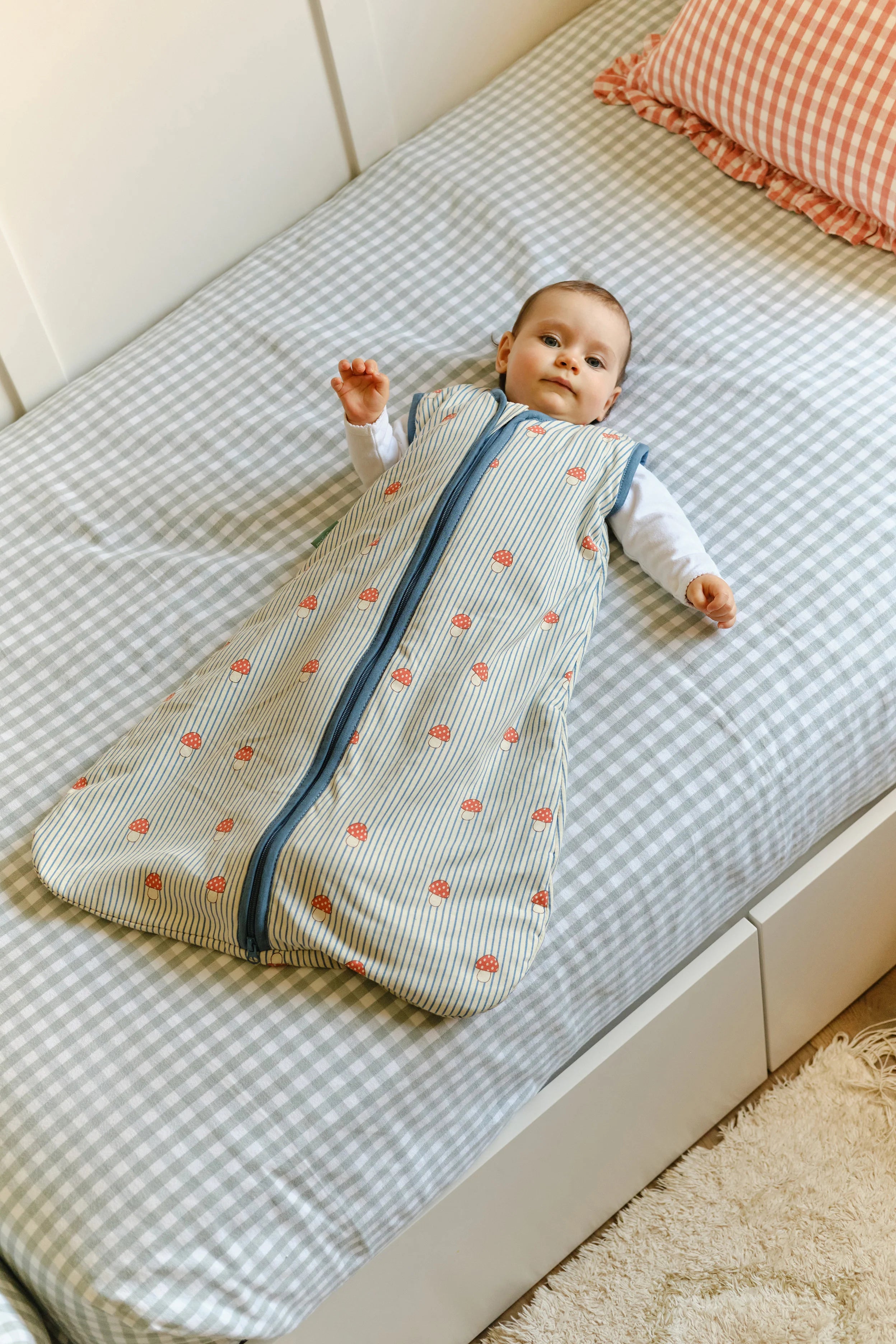 Bebé deitado de costas na cama, a usar o saco de dormir MolisandCo TOG 1.0 'Mushrooms' para um sono seguro.