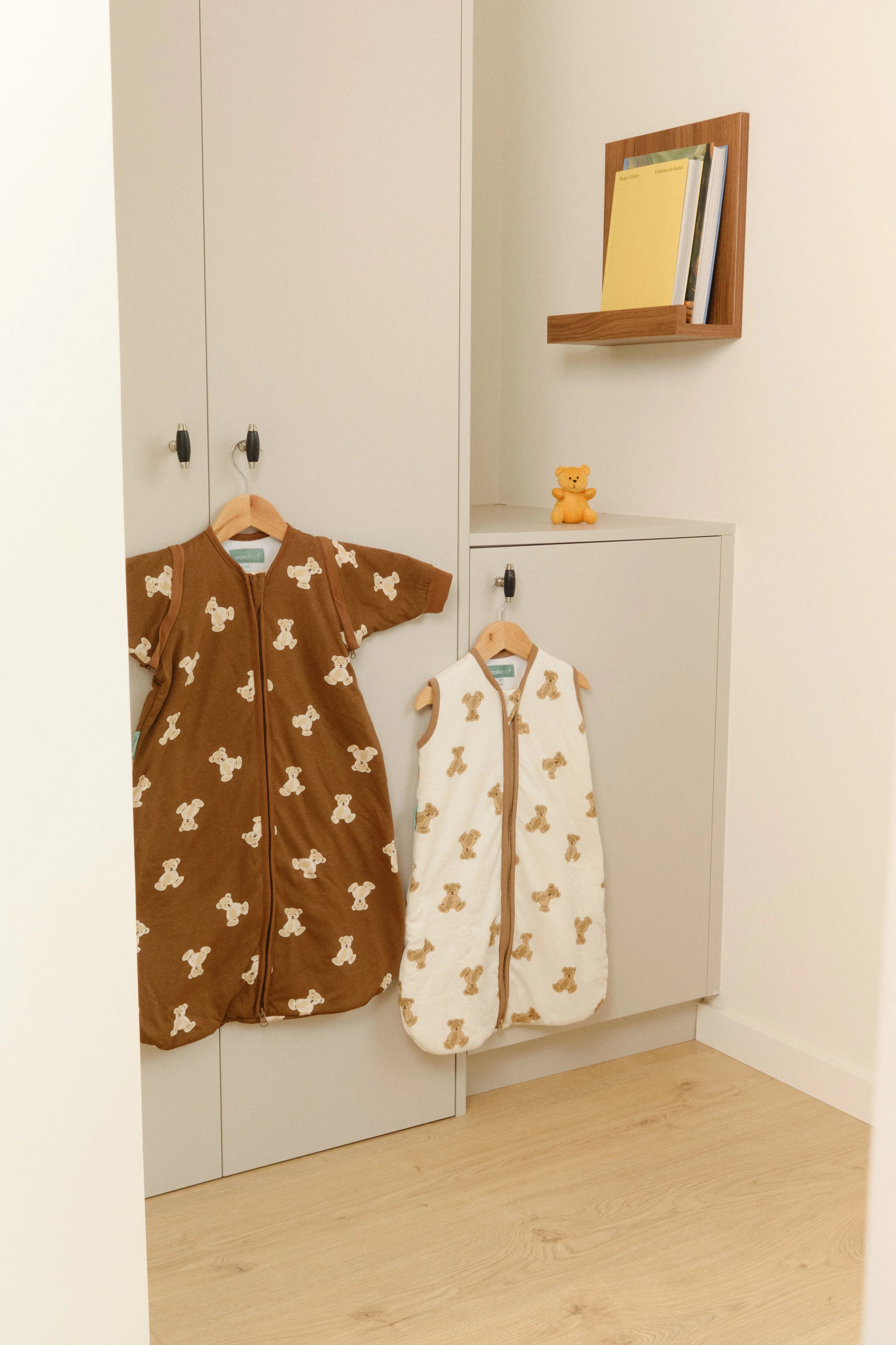 Sacos de dormir MolisandCo TOG 1.0 Teddy (creme e castanho) pendurados em quarto de criança. Design e praticidade.