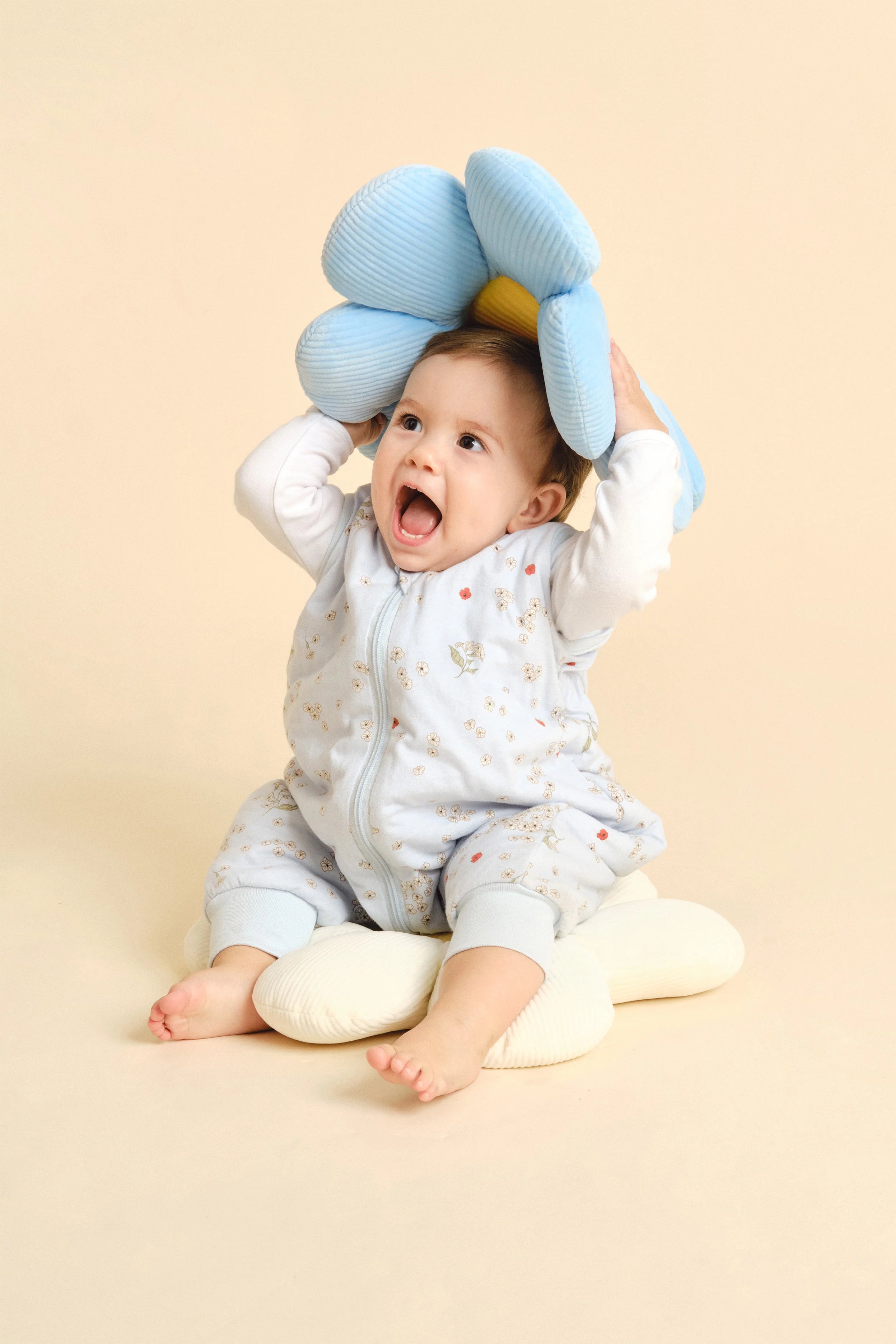 Bebé sentado, feliz, a brincar com almofada, usando saco de dormir MolisandCo TOG 1.0 Poppy.