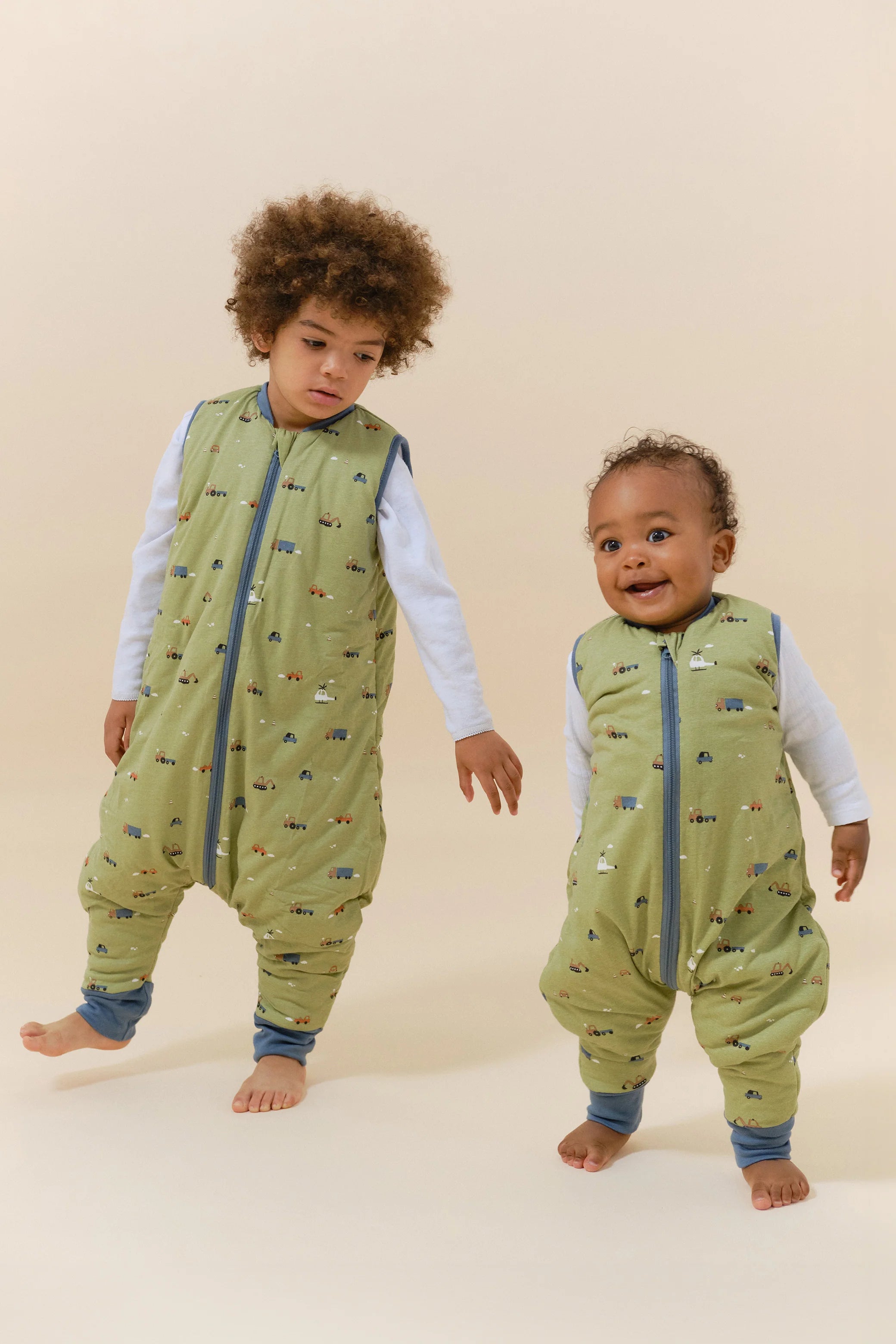 Dois bebés com sacos de dormir MolisandCo TOG 2.5 com pés Little Drivers, a brincar, mostrando liberdade de movimento.