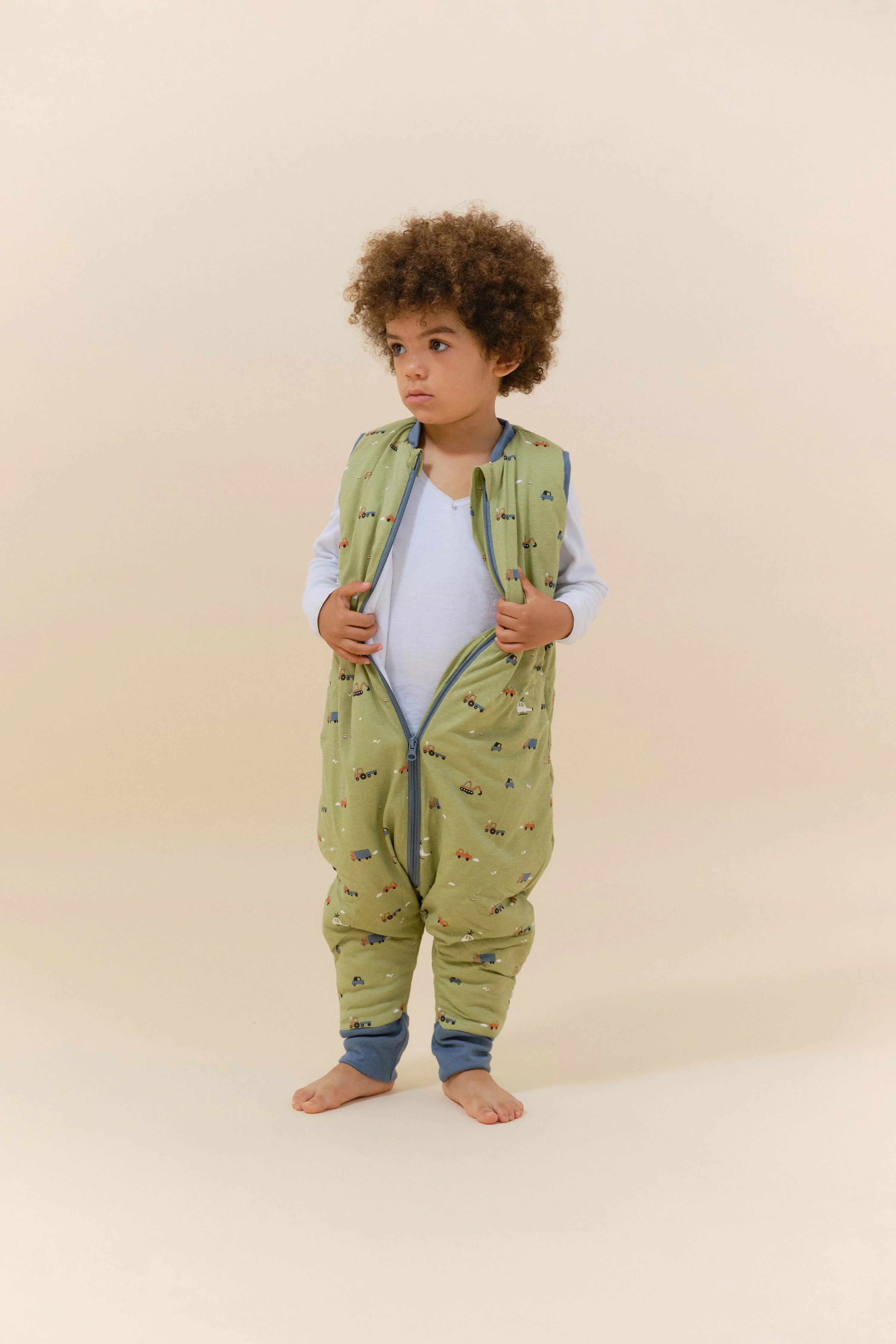 Criança com saco de dormir MolisandCo TOG 2.5 com pés Little Drivers, fecho frontal semiaberto, para vestir fácil.