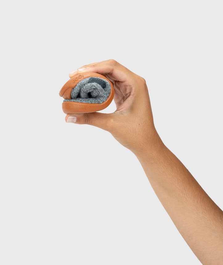 Pantufa dobrada na mão, demonstrando a sua flexibilidade extrema, essencial para respeitar a mobilidade natural dos pés e garantir conforto.