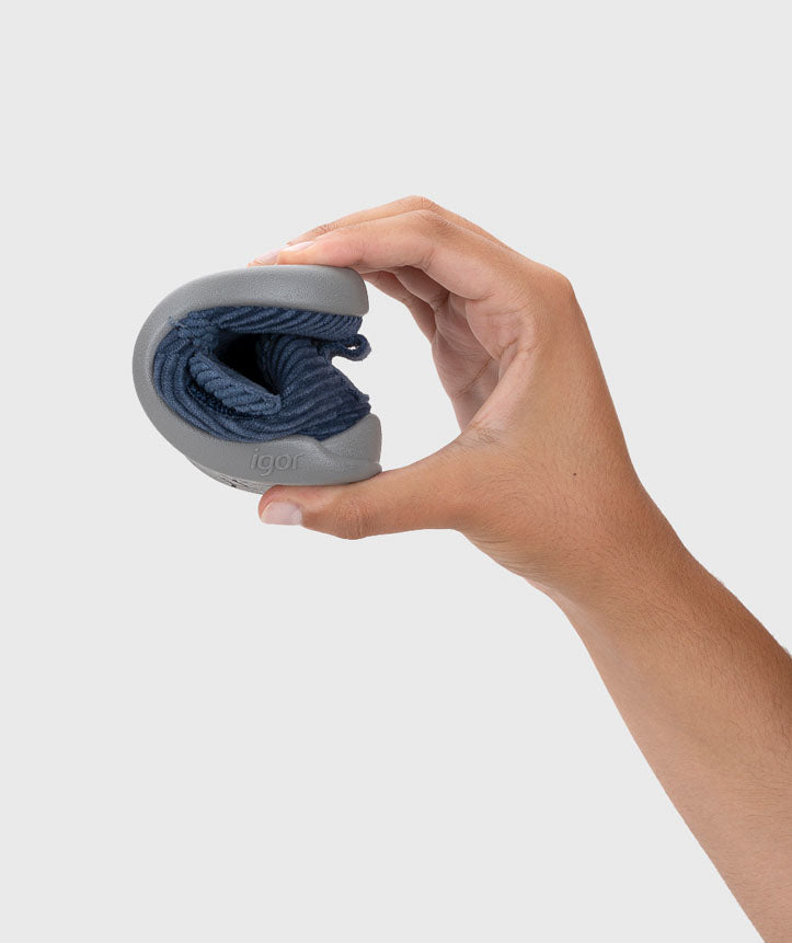 Pantufa dobrada, evidenciando a sua extrema flexibilidade, essencial para respeitar a mobilidade natural dos pés e promover um desenvolvimento saudável.