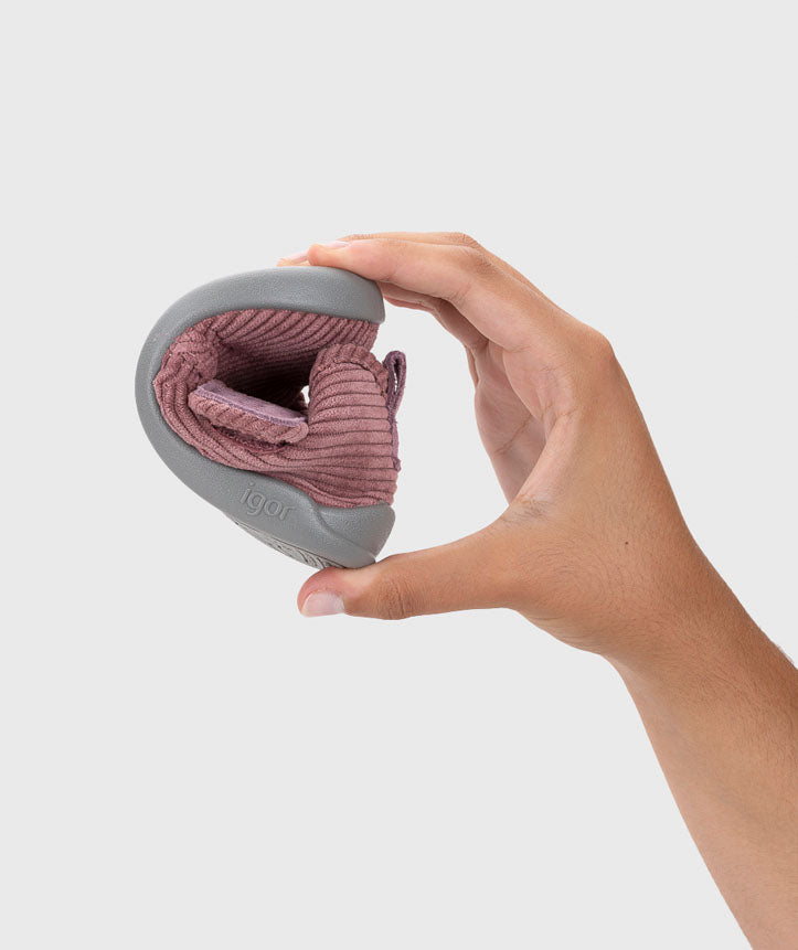 Pantufa dobrada na mão, demonstrando a sua flexibilidade extrema, essencial para um calçado respeitador que promove o desenvolvimento saudável dos pés.