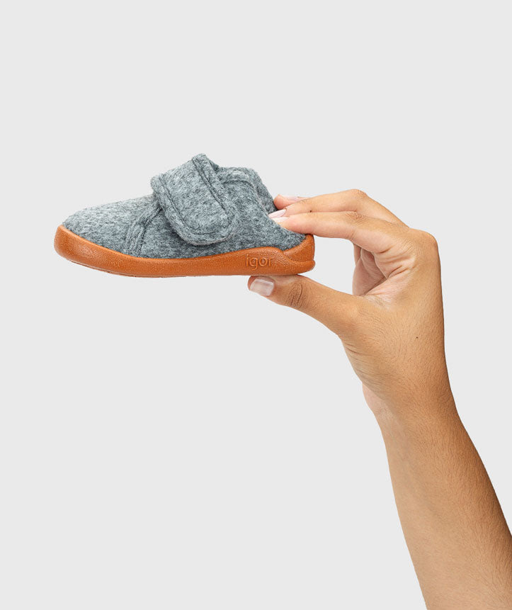 Pantufa segurada na mão, mostrando a leveza e a flexibilidade do material, ideal para promover um ajuste natural e confortável.