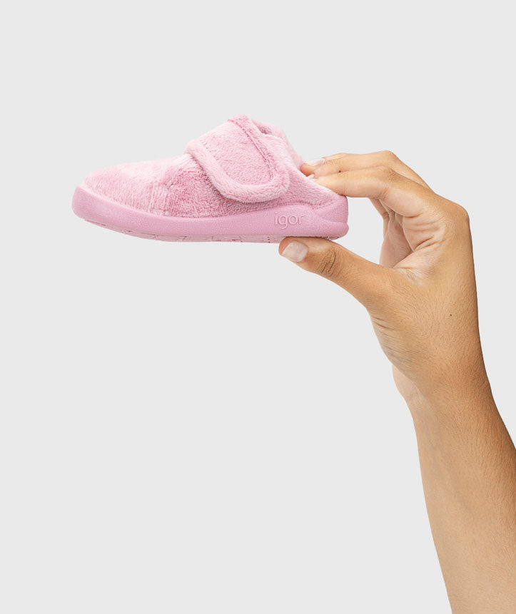 Pantufa segurada na mão, evidenciando a leveza e maleabilidade do material, garantindo um ajuste confortável e natural ao pé da criança.