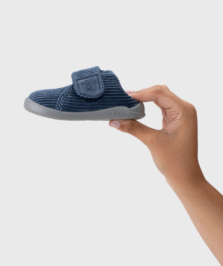 Pantufa segurada na mão, mostrando a leveza e flexibilidade do material, garantindo um ajuste confortável para os pés das crianças.