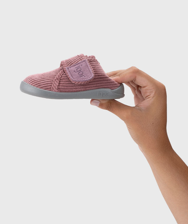 Pantufa segurada na mão, destacando a leveza e o fecho em velcro largo, garantindo um ajuste fácil e prático para os mais pequenos.