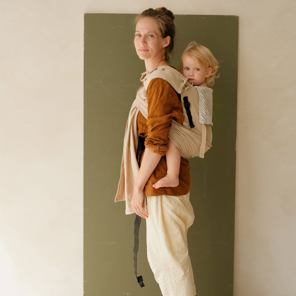 Uma mãe a carregar o seu bebé à frente, utilizando o Mei Tai Evolutivo Neobulle P'tit Evo Savane.