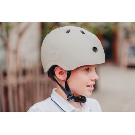 Vista lateral de criança com capacete Scoot & Ride bege 45-51cm (2-5 anos), mostrando ajuste.