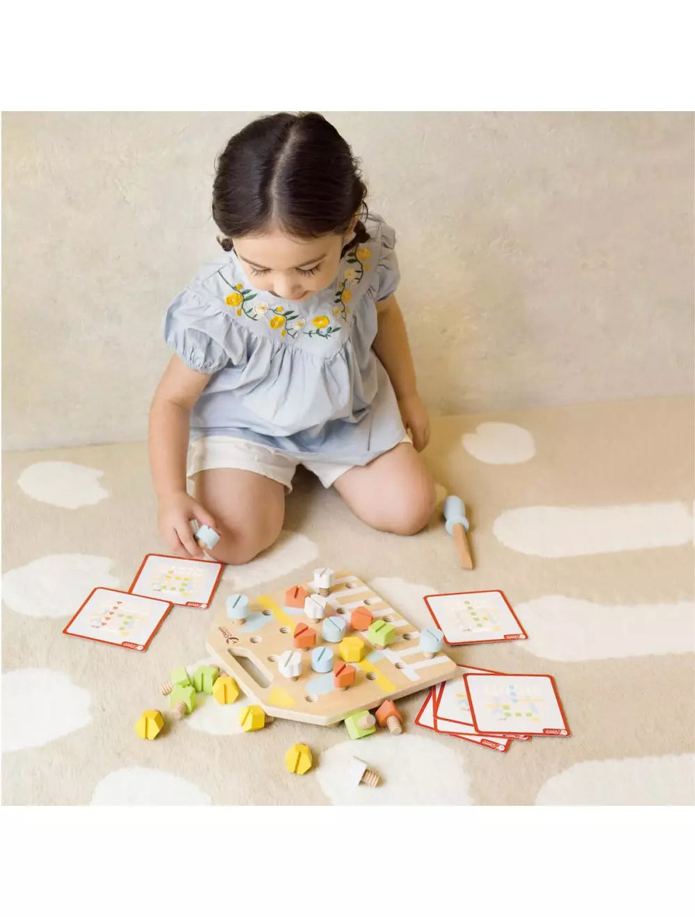 Menina concentrada a brincar com a tábua de parafusos Classic World, utilizando as cartas de padrão.