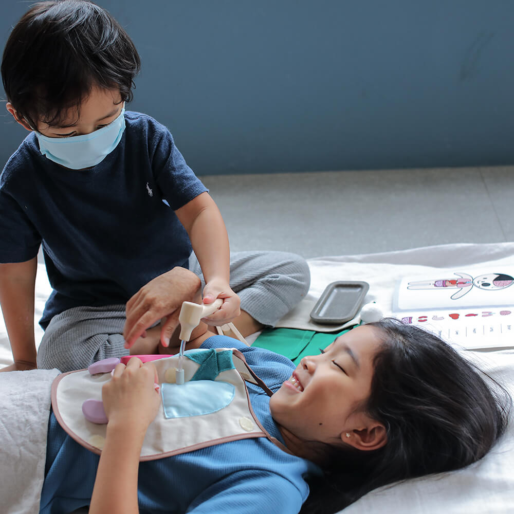 Duas crianças brincando com o conjunto cirúrgico PlanToys, mostrando o uso interativo e imaginativo do brinquedo.