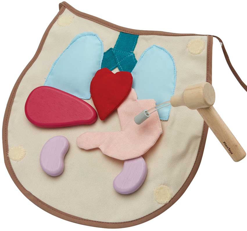 Close-up do martelo de madeira e do avental com os órgãos do conjunto cirúrgico PlanToys, mostrando a qualidade da madeira e o detalhe das peças.