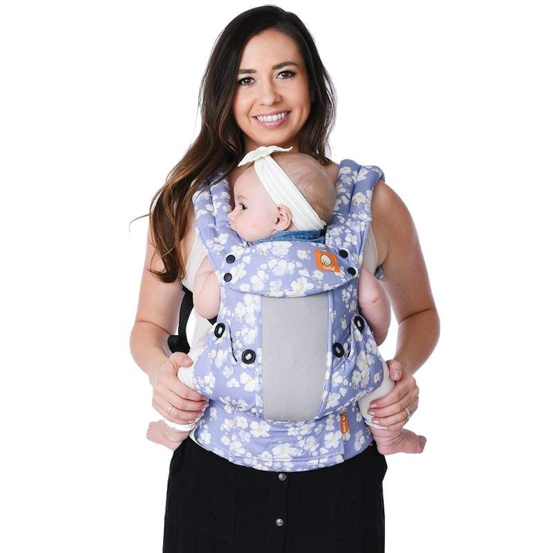 Mãe feliz carregando bebê em porta-bebê floral azul e branco Gotu, mostrando diferentes posições de babywearing.