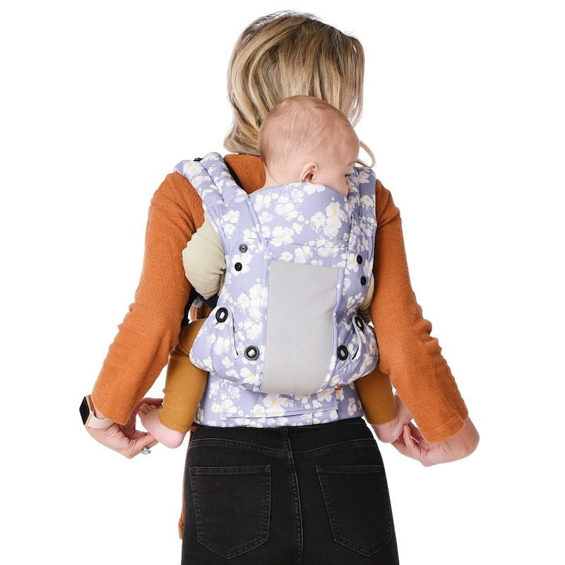 Vista traseira de mãe com bebê no porta-bebê floral azul e branco Gotu, demonstrando ergonomia e segurança.