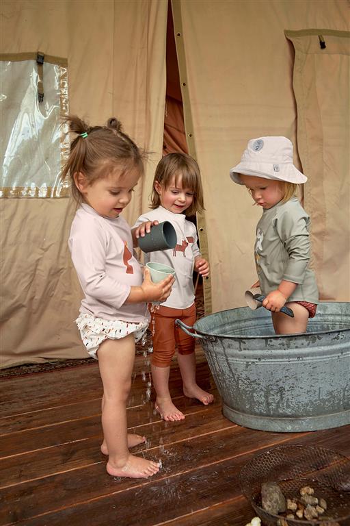 Crianças a brincar com chapéu Lassig UV 80, ideal para proteção solar na praia ou piscina.