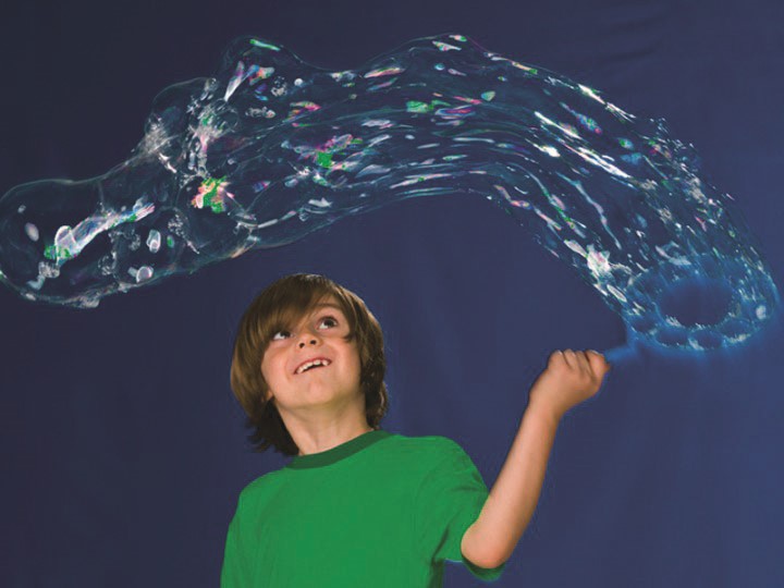 Criança brincando com o Pustefix Multi Bubbler, criando uma longa e fina bolha de sabão.
