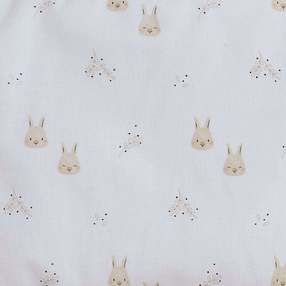 Detalhe de um padrão de tecido infantil com pequenos coelhos e elementos botânicos, ilustrando opções de design.