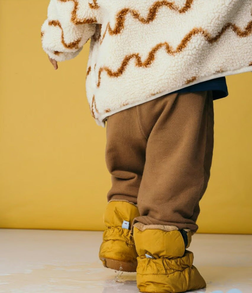 Um par de botas barefoot cor-de-rosa com detalhes texturizados, colocadas sobre um fundo branco.